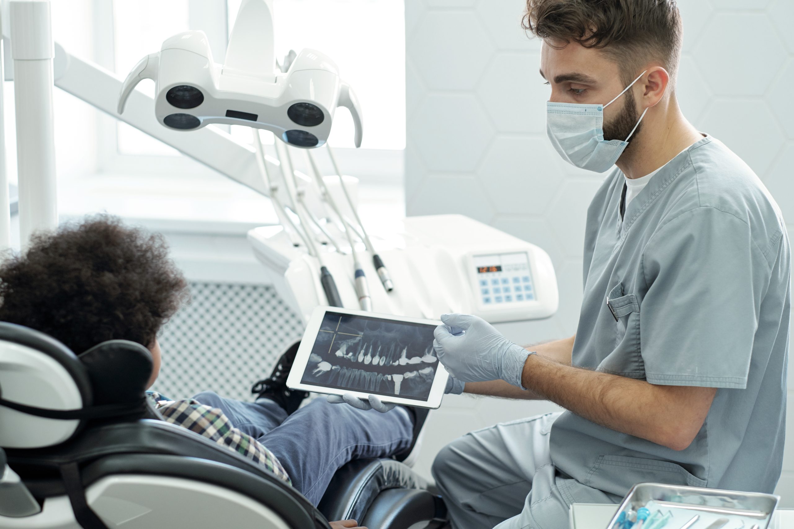 Dentist In Mask, Gloves And Uniform Interacting With Little Patient